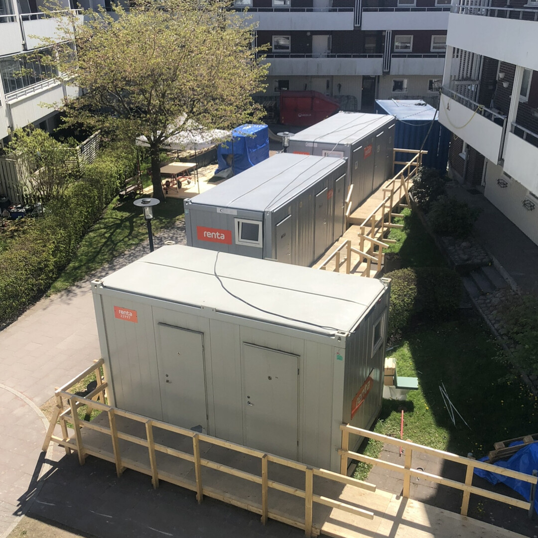 Tillfälliga evakueringsbodar uppställda i en innergård med omgivande byggnader och träd