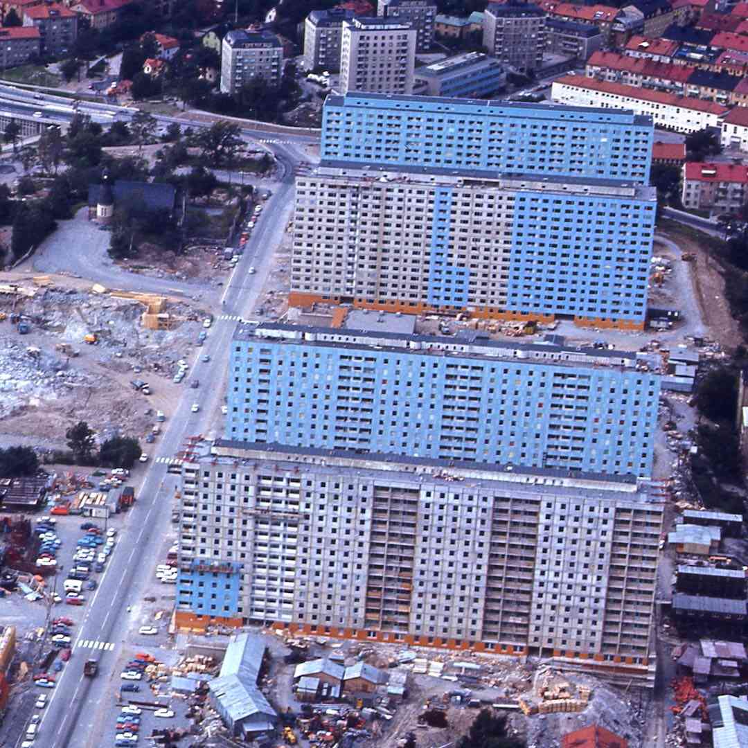 Flygfoto av ett område med höghus under konstruktion, omgivna av stadsbebyggelse och vägar