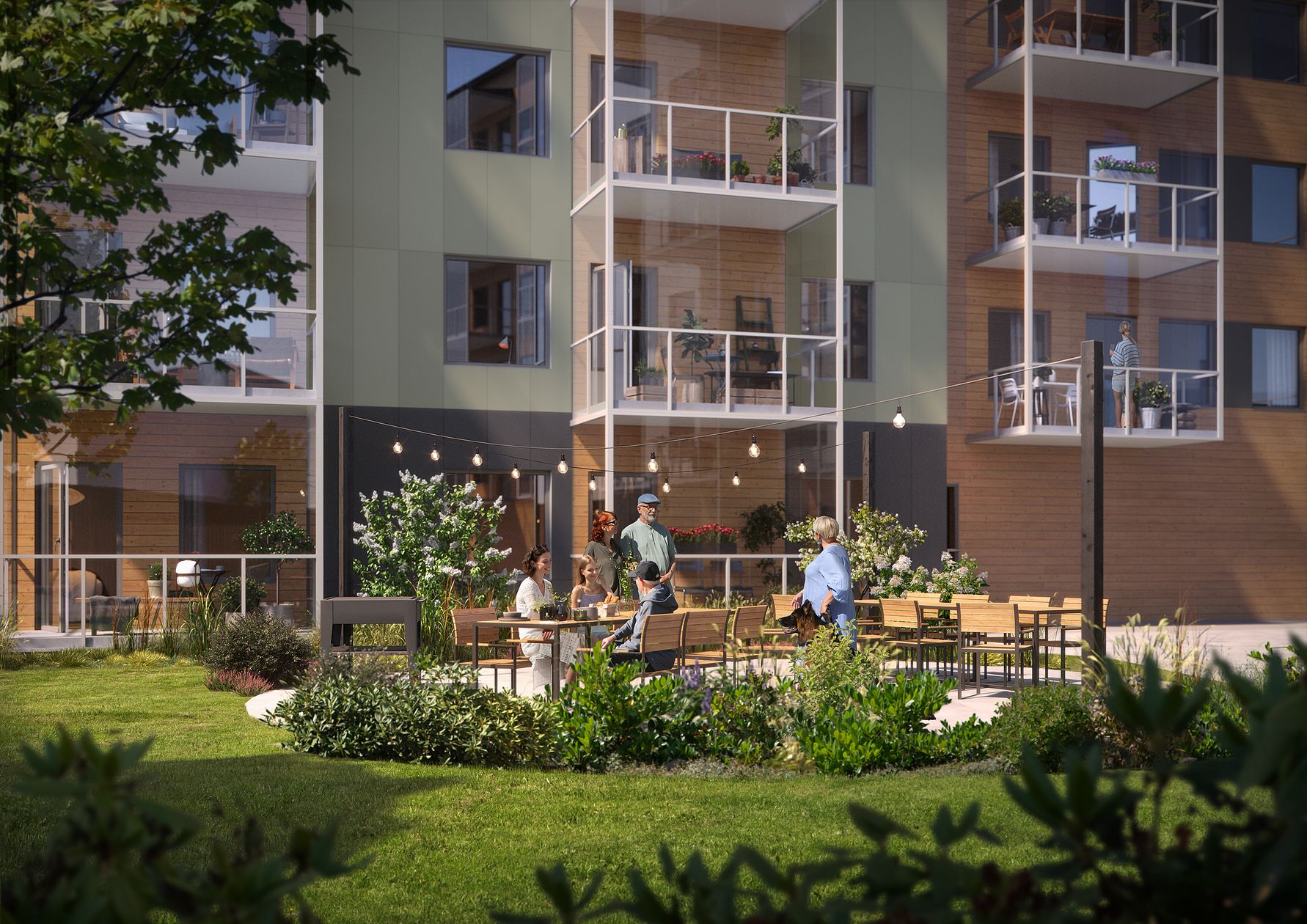 En grönskande innergård med sittmöbler, omgiven av moderna lägenhetsbyggnader med balkonger. Flera personer sitter och står vid borden under hängande ljusslingor