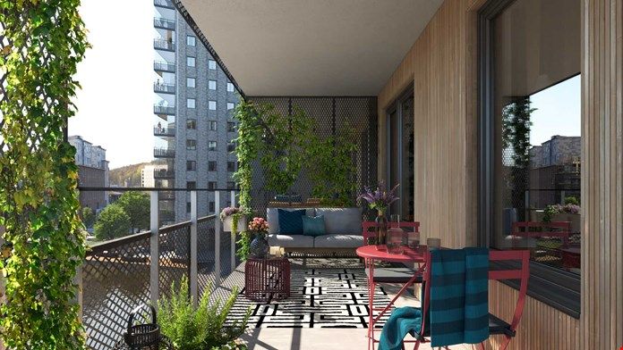 Balkong med trädäck, sittplatser, gröna växter och utsikt över ett bostadsområde med flerbostadshus