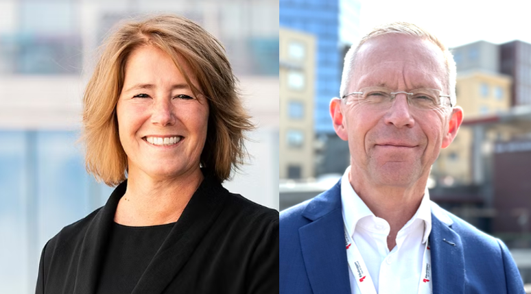 Två personer i formella kläder står framför en bakgrund med byggnader och glasfasader