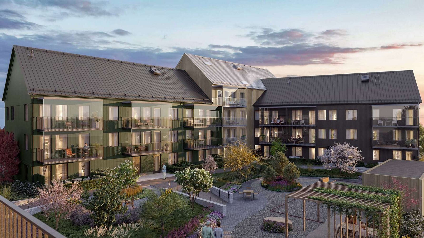 Bostadskomplex med tre moderna byggnader, omgivna av en grön och öppen gård med växter, träd och sittplatser under en kvällshimmel