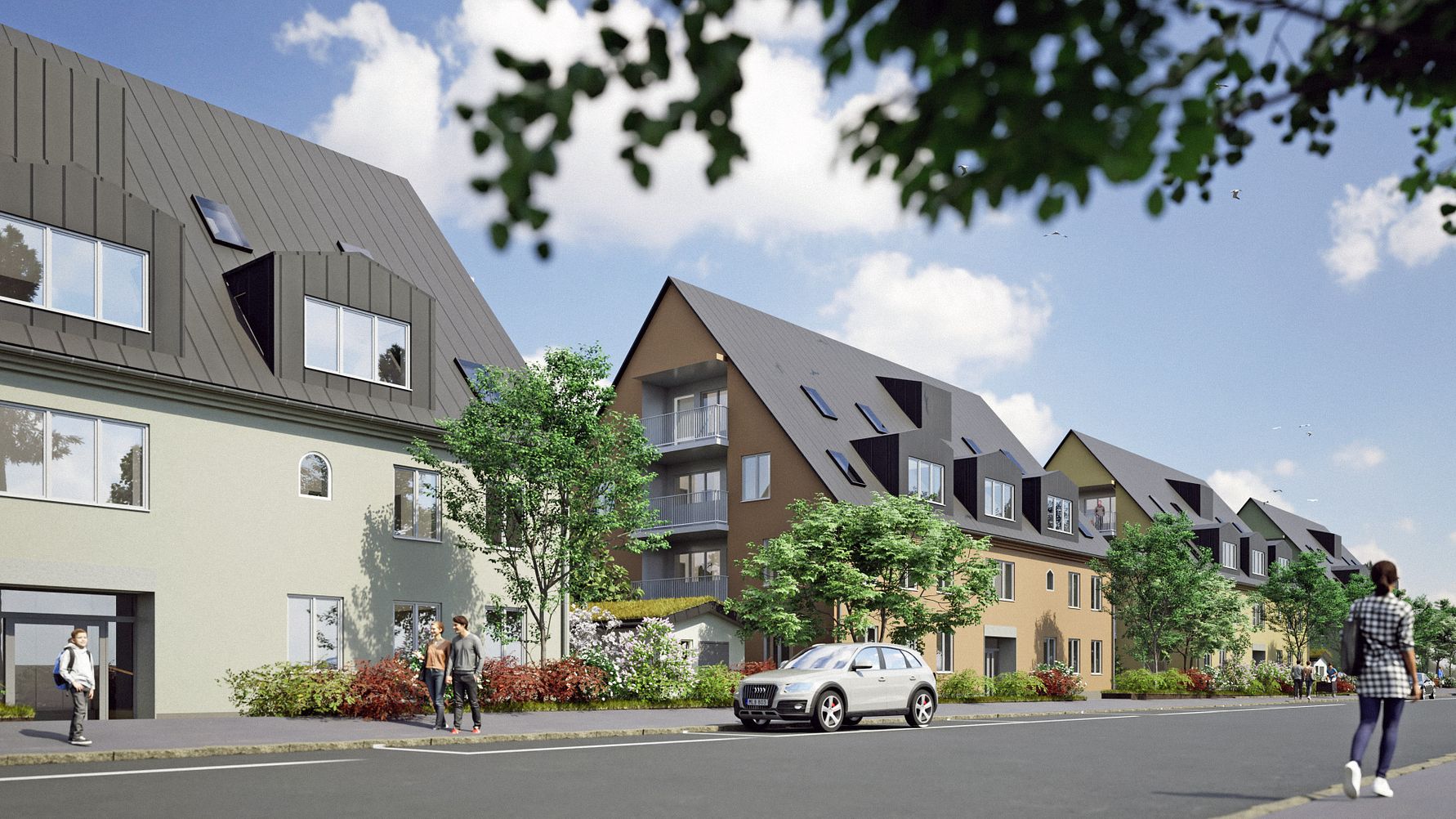 Rad av moderna bostadshus med spetsiga tak, omgivna av träd och buskar, en väg i förgrunden med flera människor och en bil