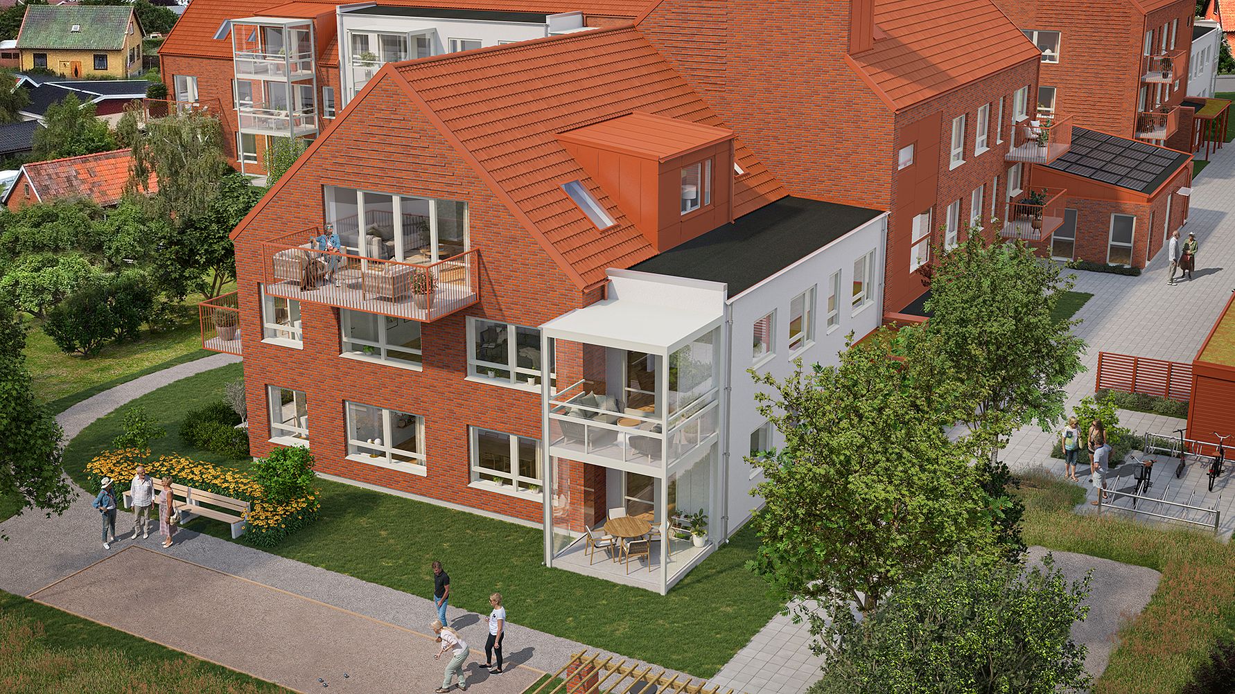 Rött flervåningshus med balkonger, stora fönster och tegelväggar, omgiven av grönska och gångvägar