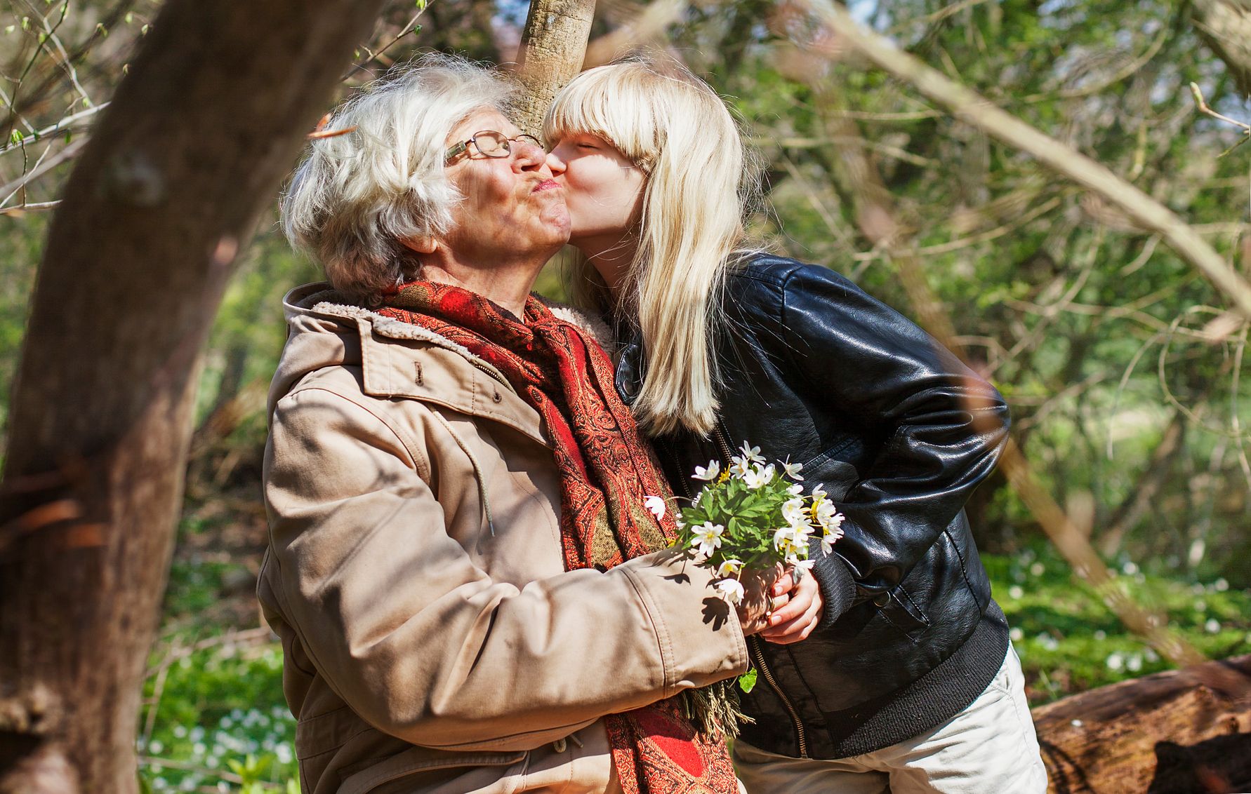 Två personer i en skog omgivna av grönska, där en av dem håller en bukett med vita blommor