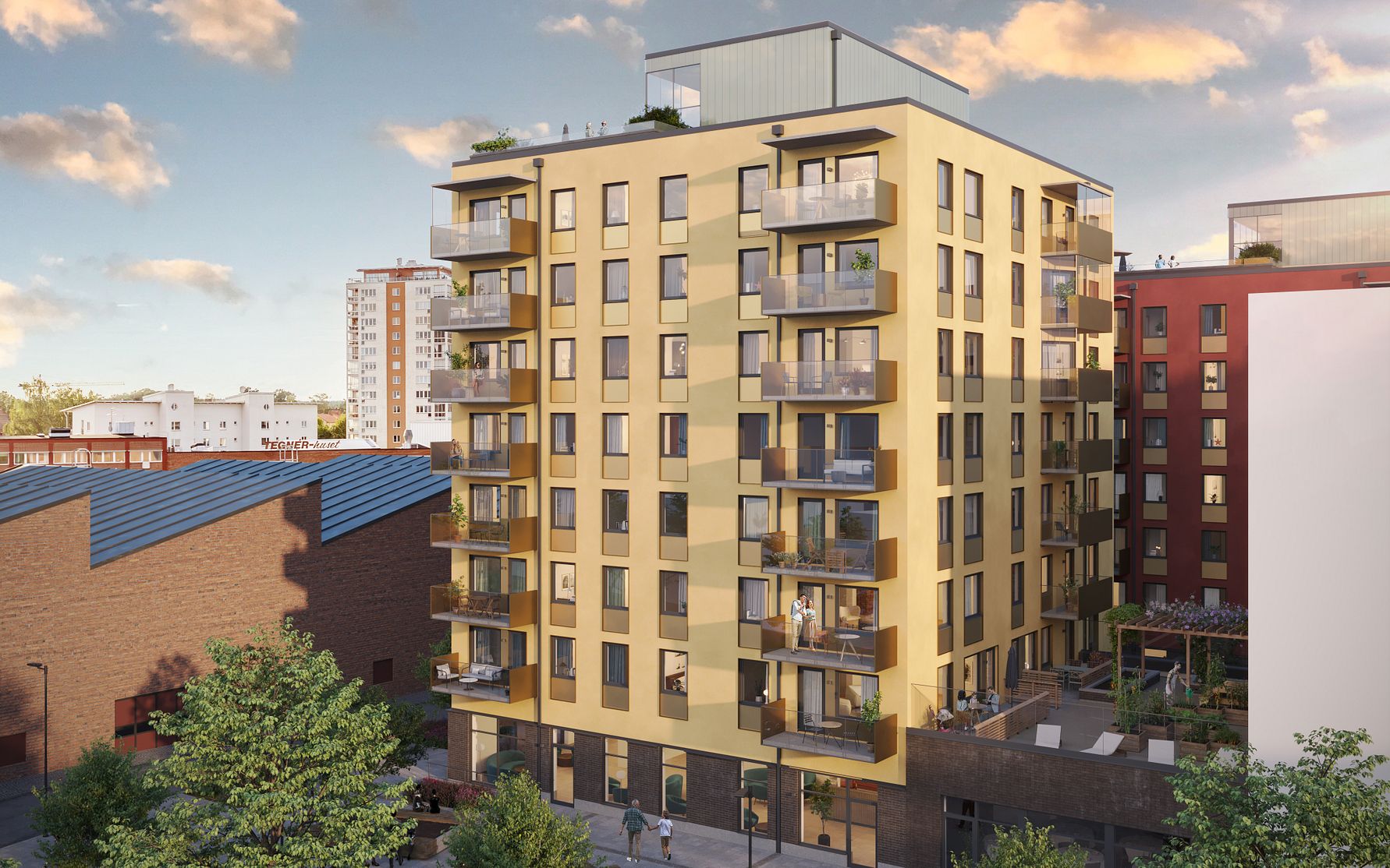 Flerfamiljshus med moderna balkonger på flera våningar, omgivna av grönska och intillliggande byggnader under en klar himmel