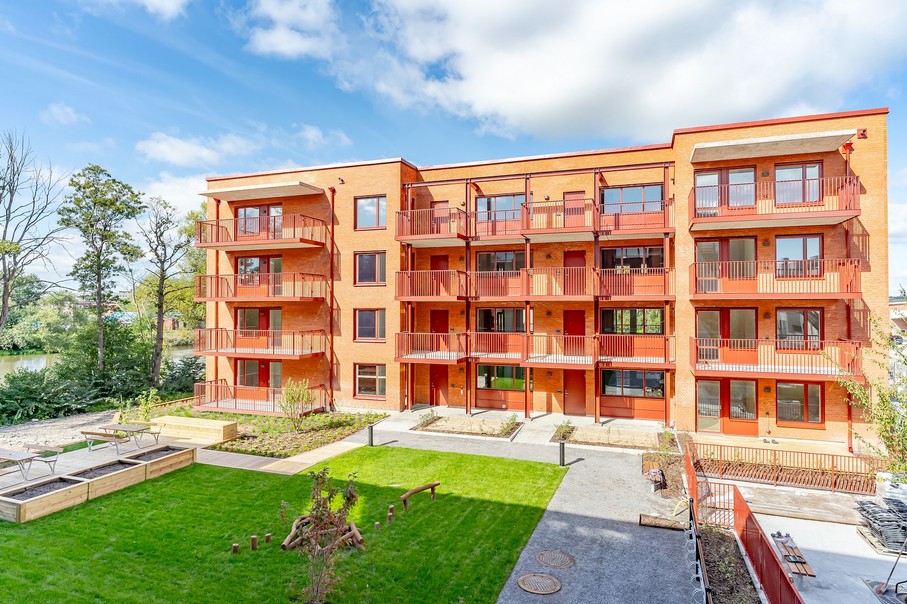 Flerfamiljshus i tegel med balkonger och en grön innergård, under en blå himmel