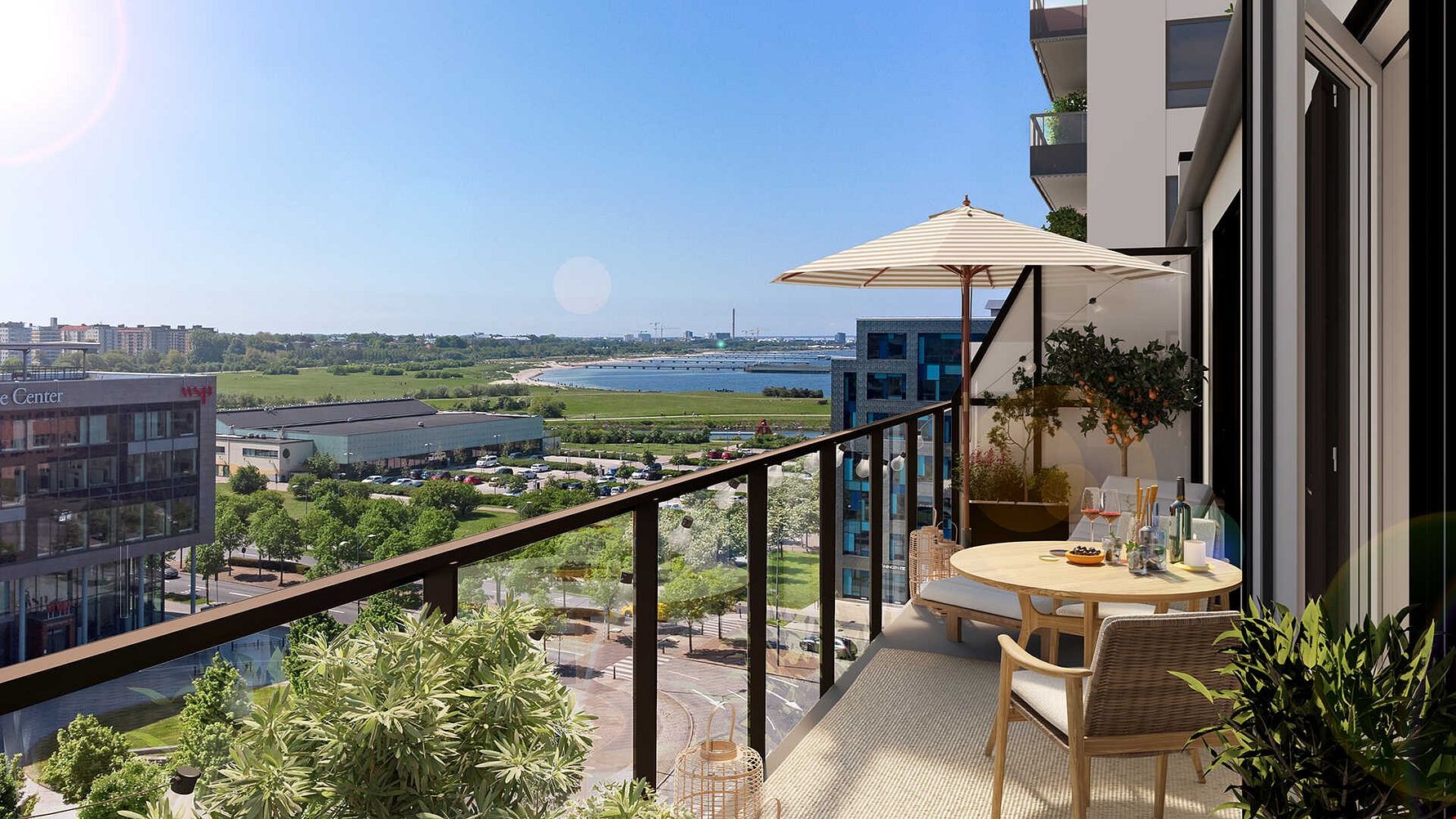 Balkong med utsikt över ett grönområde och vatten, möblerad med bord, stolar och parasoll