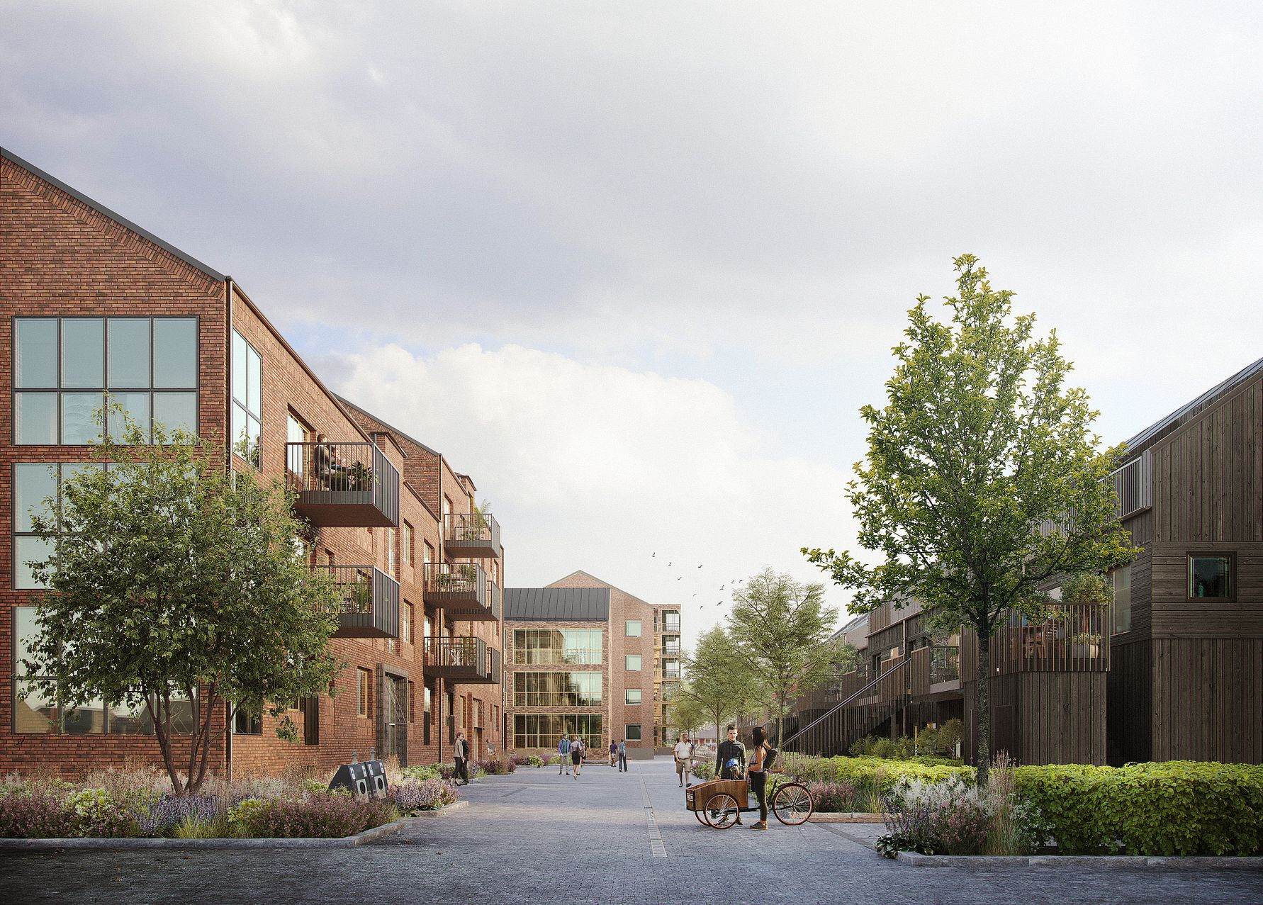 Bostadsområde med moderna byggnader i tegel och trä, omgivna av grönska och en gångväg under en ljus himmel