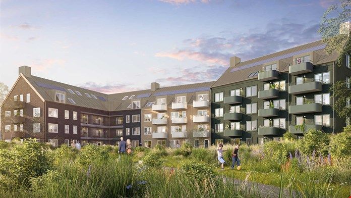 Lägenhetsbyggnader med balkonger omgivna av grönska och öppna grönområden under en klar himmel