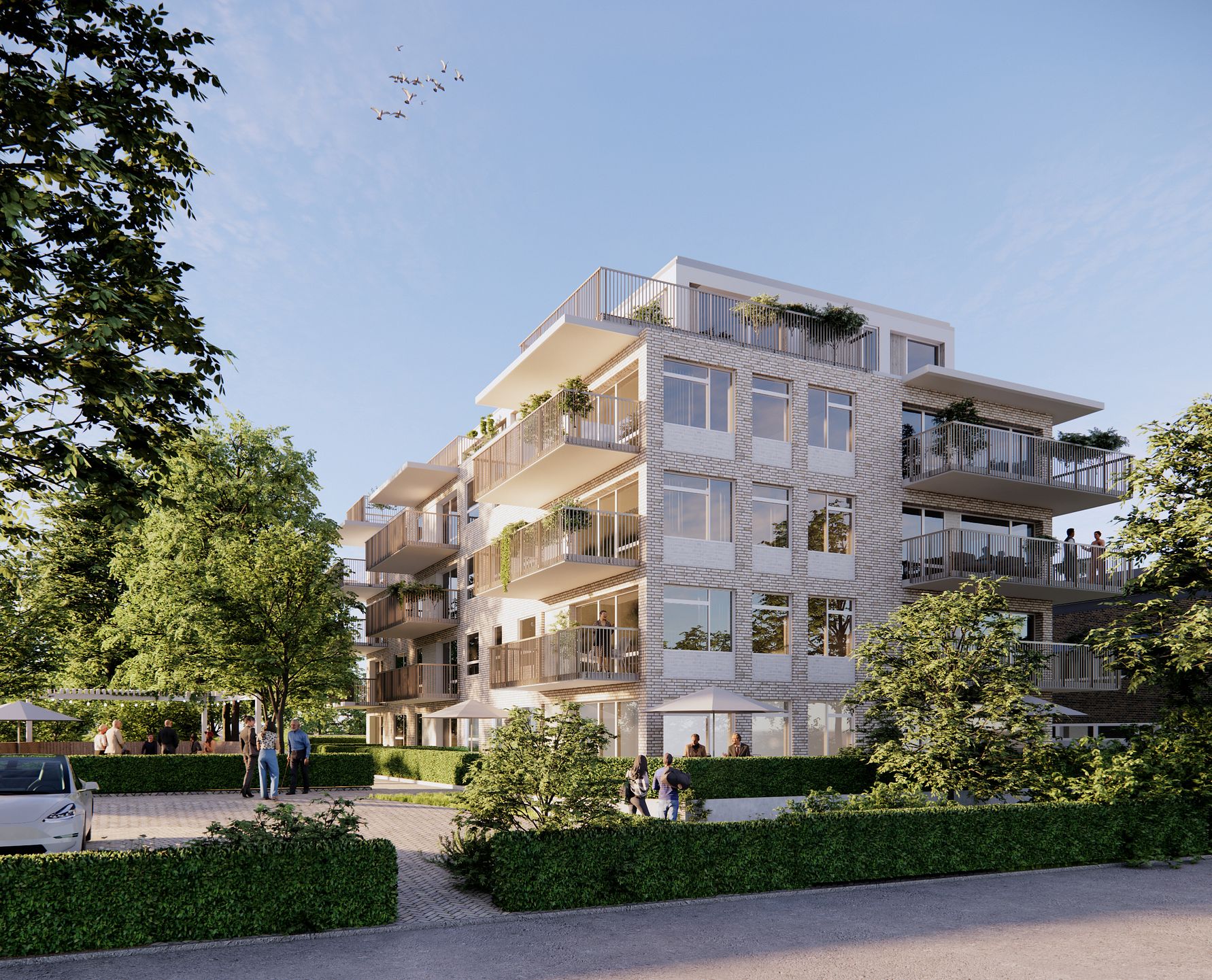 Modernt lägenhetskomplex i flera våningar med balkonger, omgiven av grönska på en solig dag