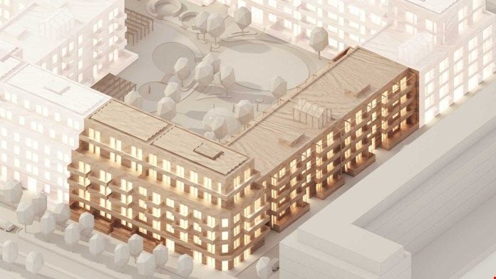 Arkitektonisk modell av ett flerfamiljshus med gårdsplan och omgivande byggnader, belyst för att framhäva strukturen