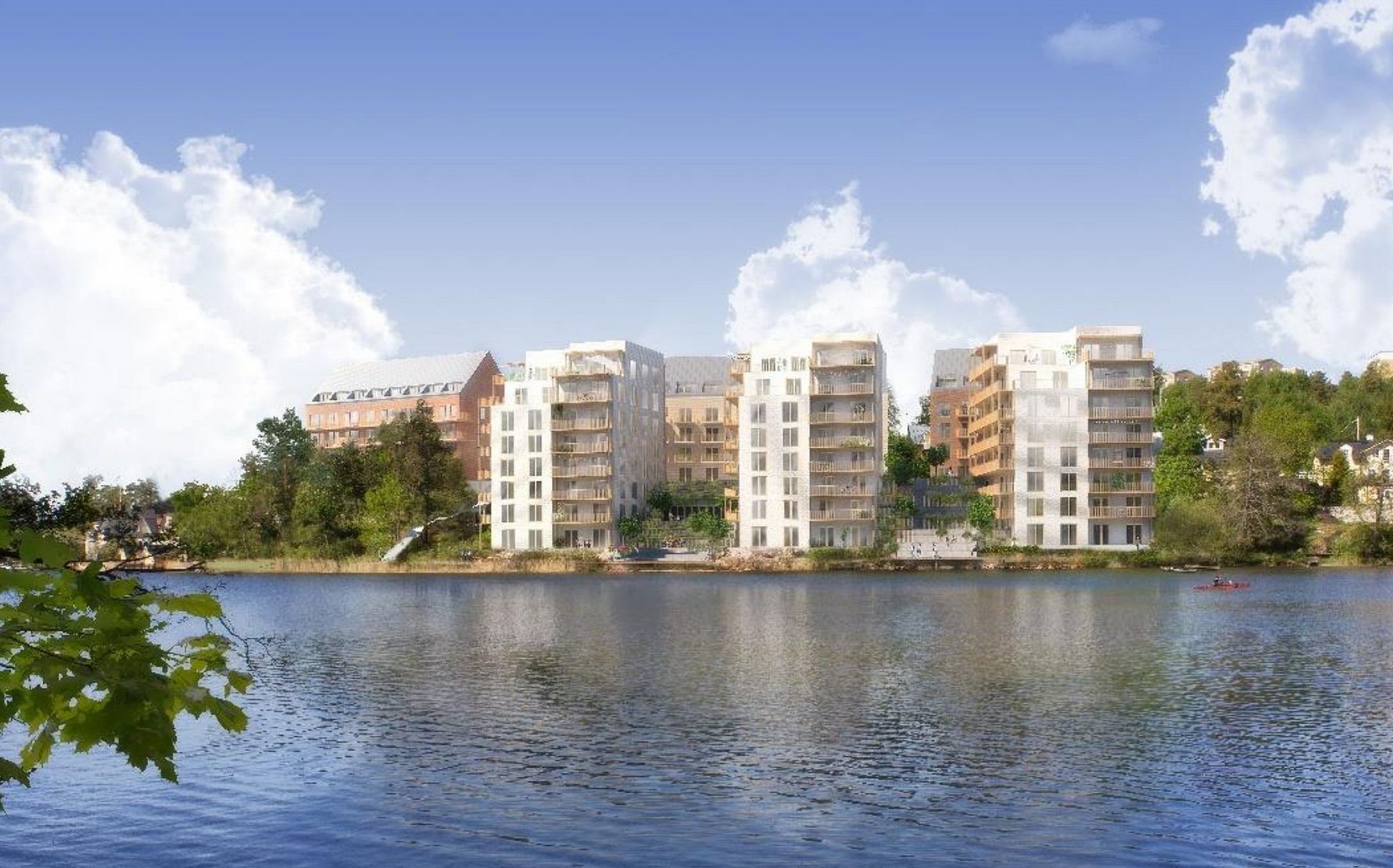Nybyggda flerfamiljshus vid vattnet, omgivna av grönska och blå himmel