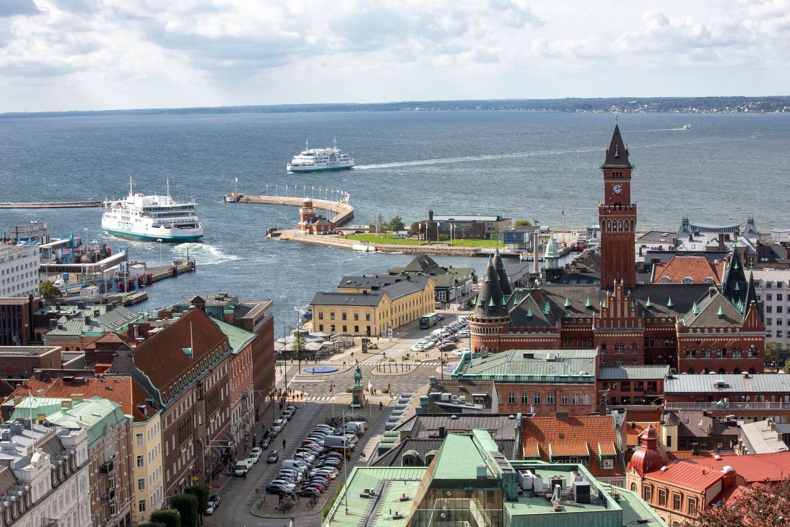 Vy över Helsingborgs hamn med färjor på Öresund, Kärnan och omgivande byggnader i centrum under en molnig himmel