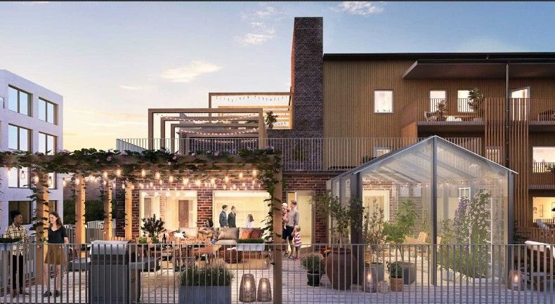 Modern bostadsområde med uteplats, pergola med belysning, växthus och byggnader i trä och glas. Människor samlade kring utomhusbord vid solnedgång