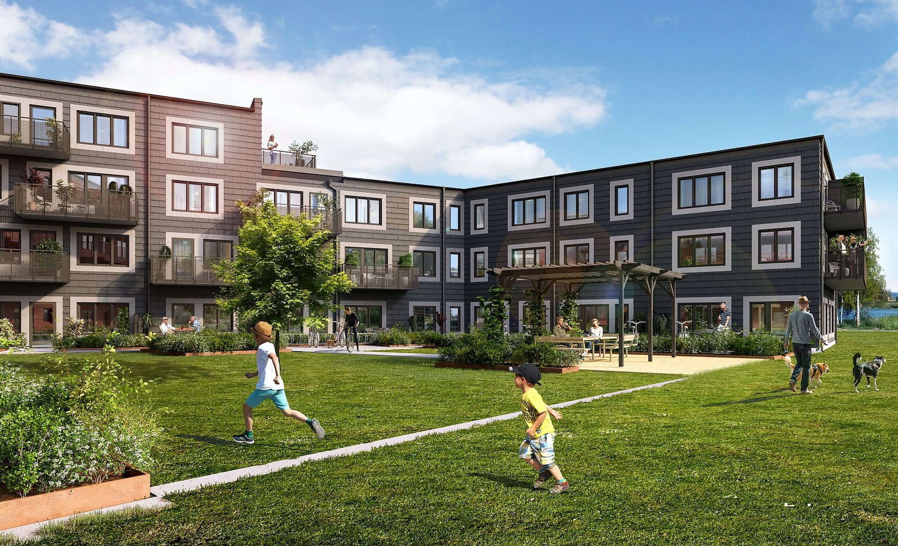 Modern bostadskomplex med tre våningar, omgiven av grönområde och lekande barn på gräsmattan under en klar blå himmel
