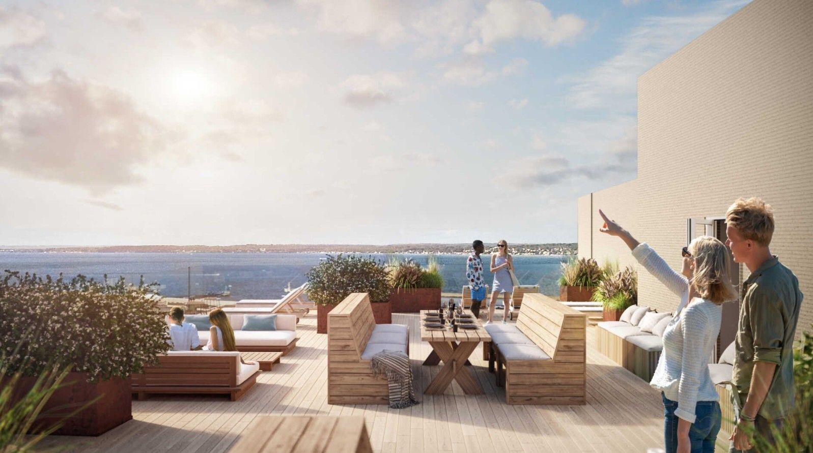 Modern takterrass med trämöbler, en sittgrupp och utsikt över havet under en solig dag. Flera personer syns umgås på terrassen