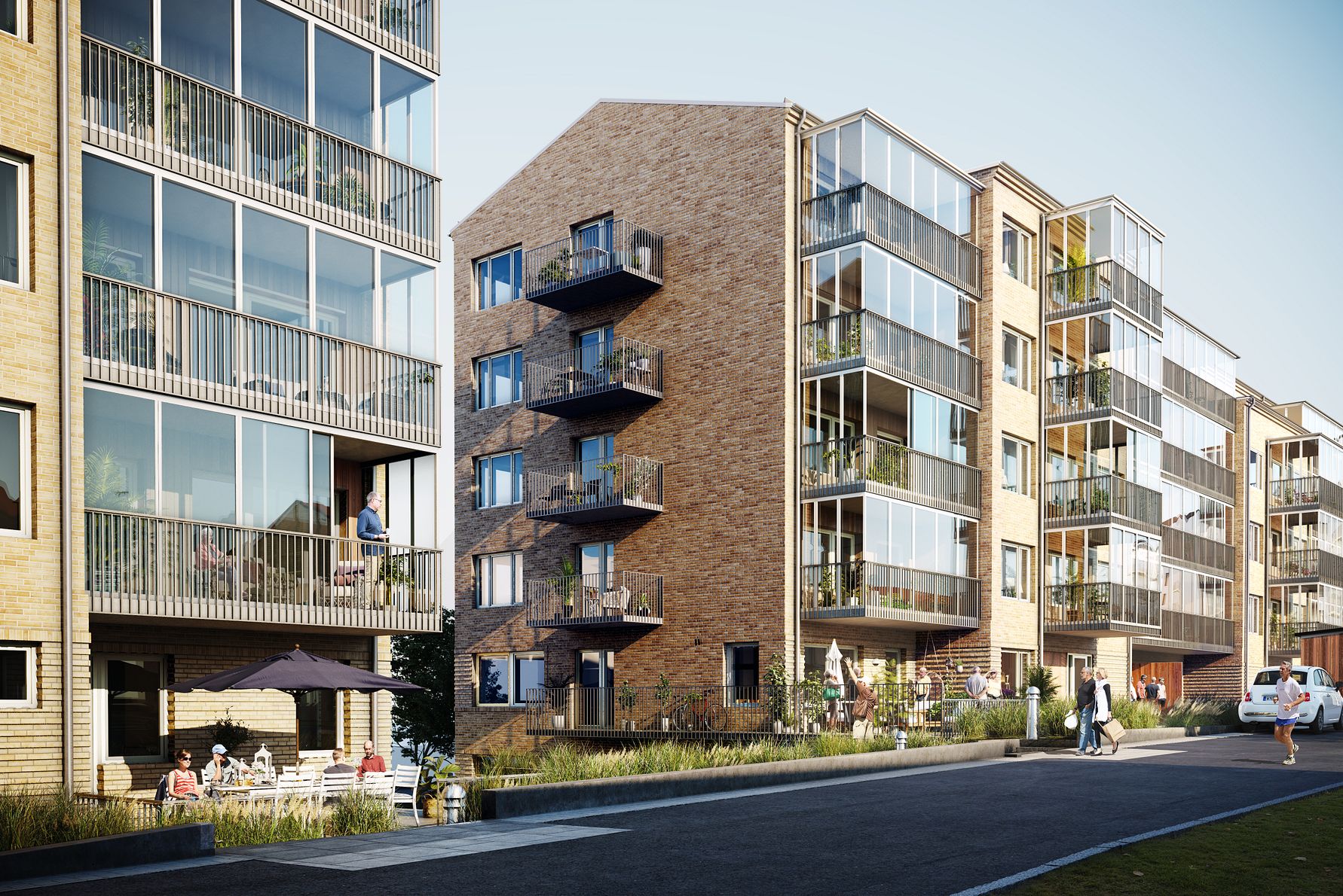 Nybyggda flerfamiljshus med fasader av tegel och glas, omgivna av grönska och gångväg