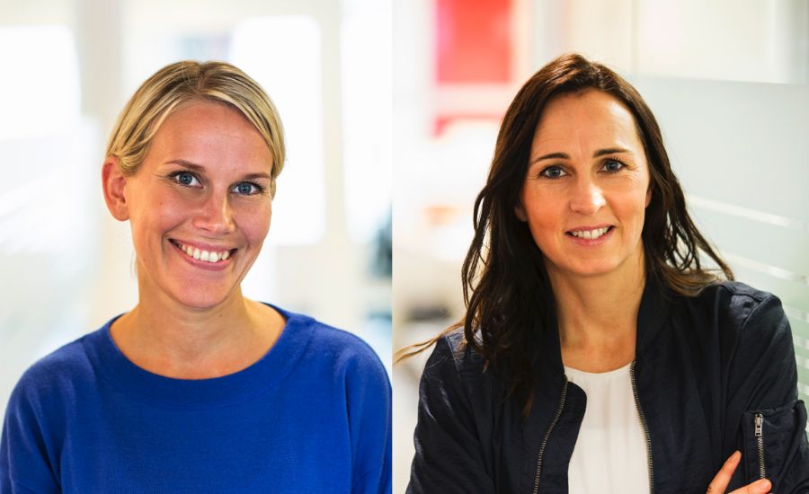 Två personer i ett kontorsutrymme, den vänstra personen bär en blå tröja och den högra personen bär en mörk jacka över en vit topp