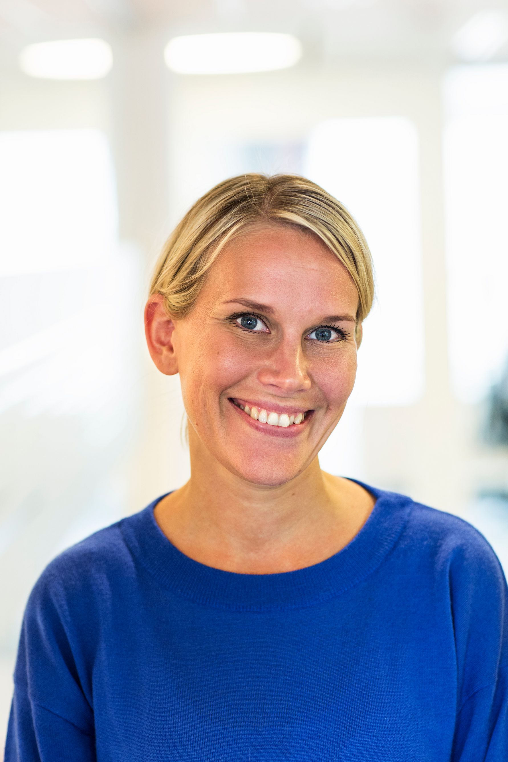 Kvinna i en blå tröja med ljus bakgrund inomhus