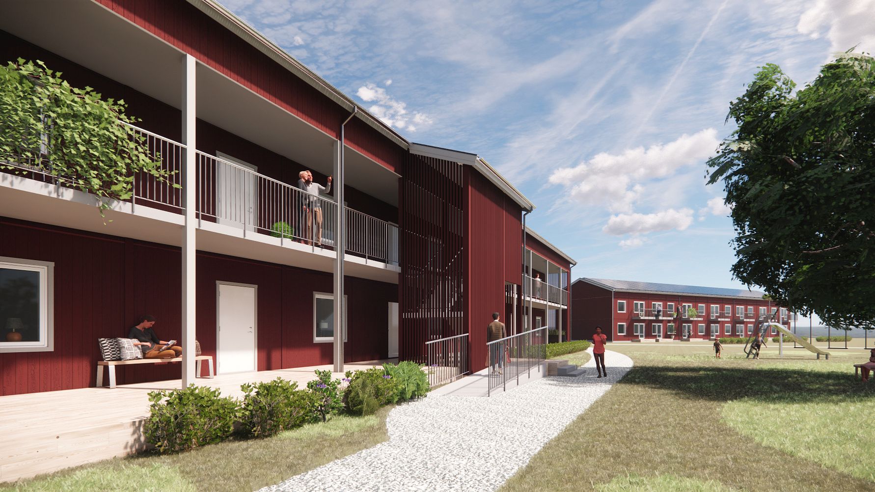 Tvåvåningsbyggnader i röd träfasad med balkonger, omgivna av gröna gräsmattor och träd under en klarblå himmel