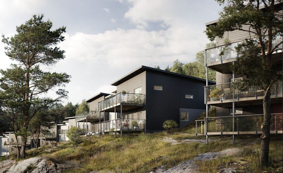 Flera moderna bostadshus med glasbalkonger på en sluttning omgiven av träd och grönska