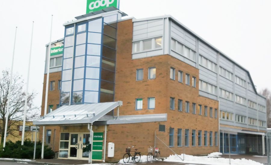 Byggnad med en Coop-butik på bottenvåningen, tegelfasad, stora glaspartier och snö på marken