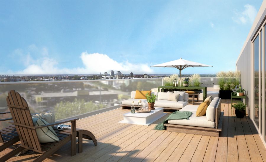 Nyrenoverad takterrass med trätrall, solstolar, soffgrupp och parasoll, med utsikt över en stad och blå himmel