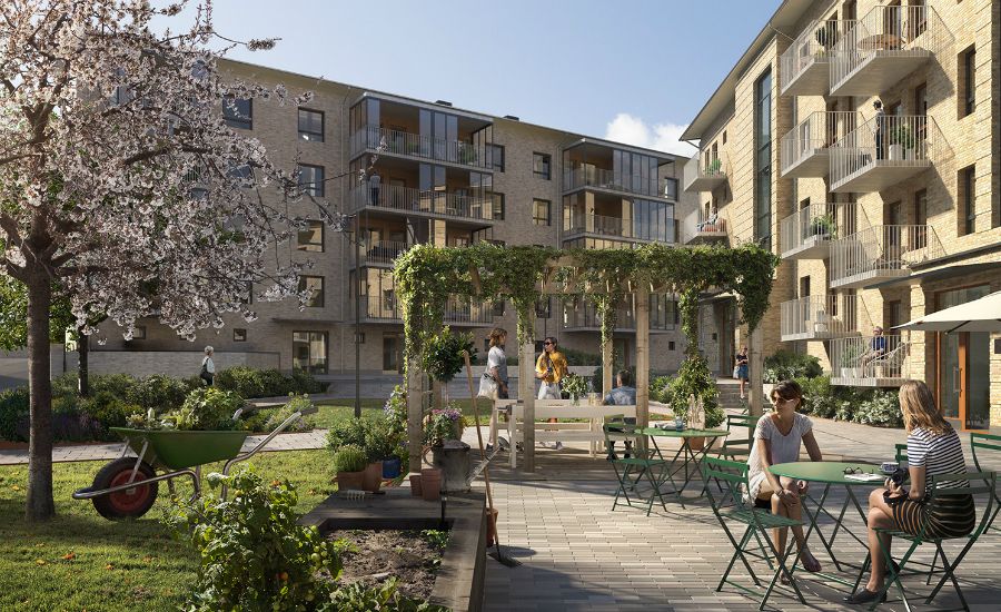 Flerbostadshus i sten med balkonger, grönskande innergård med pergola, trädgårdsmöbler och människor i en social miljö