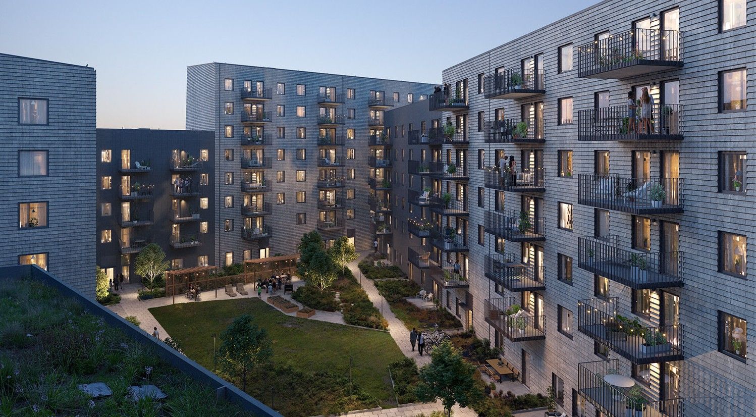 Modern flerbostadshus med grå fasader och flera balkonger, omgivna av en innergård med grönska och gångvägar