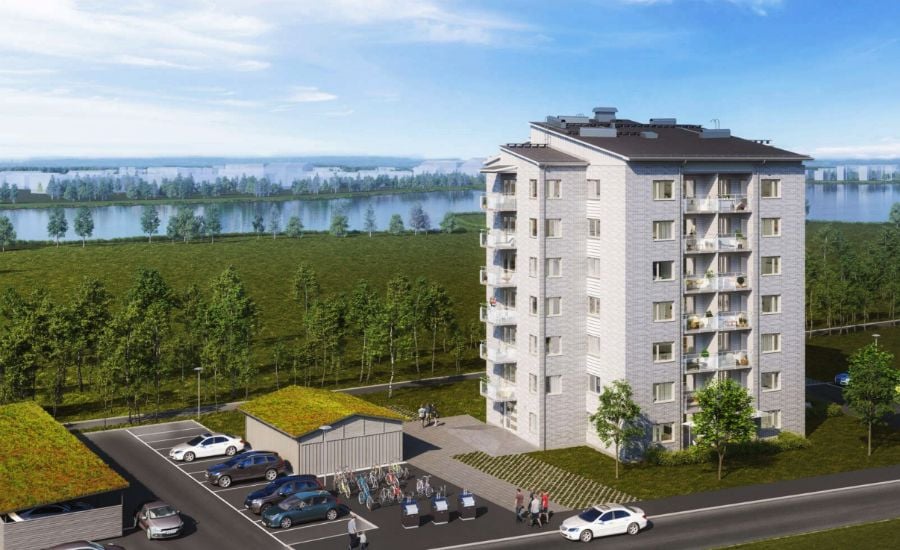 Flerbostadshus med sex våningar, parkeringsplatser och cykelförvaring, beläget vid en grönskande natur och en sjö i bakgrunden