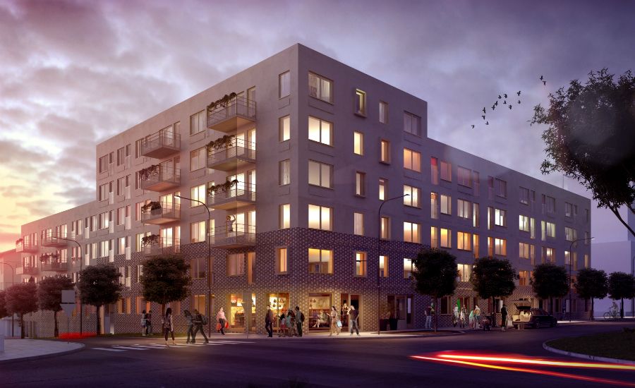 Flerfamiljshus vid en gata i skymningsljus, med upplysta fönster och människor som går längs trottoaren