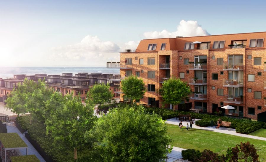 Flera flerfamiljshus i tegel med balkonger, grönskande träd och öppna gräsmattor i en modern bostadsområde