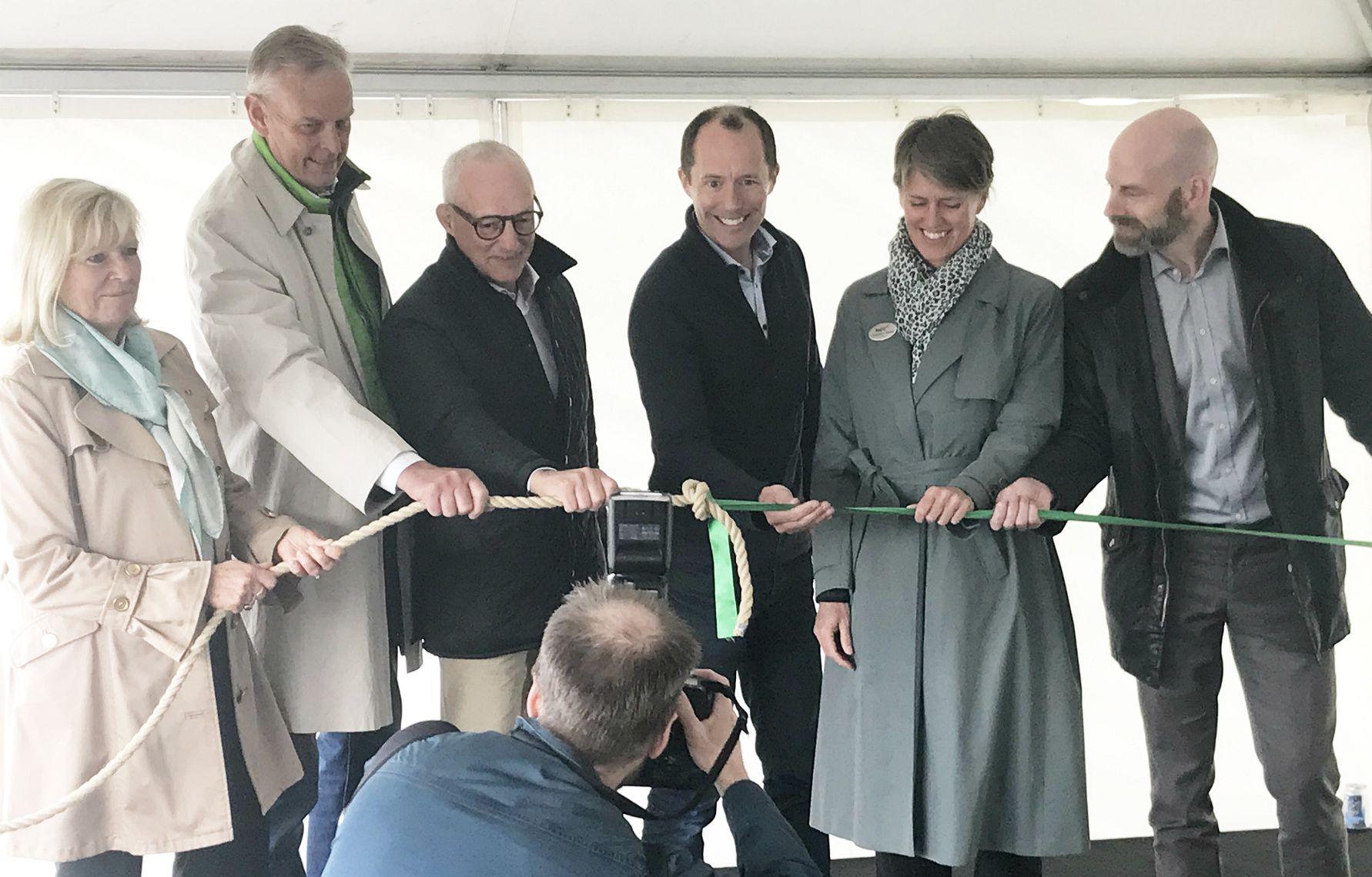 En grupp människor klipper ett band under en ceremoni, med en fotograf i förgrunden