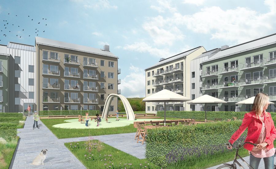 Modern bostadsområde med flerfamiljshus, lekplats med gräsmatta och sittplatser under parasoller. Personer och en hund syns i området, samt en kvinna med cykel i förgrunden