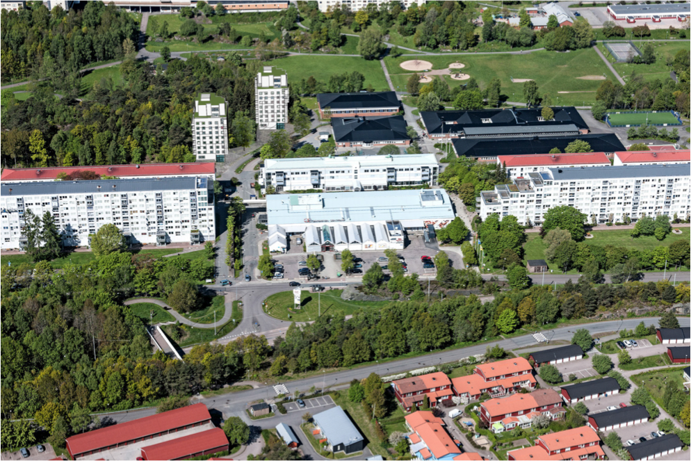 Flygfoto över ett bostadsområde med flerfamiljshus, gröna parkområden och omgivande vägar