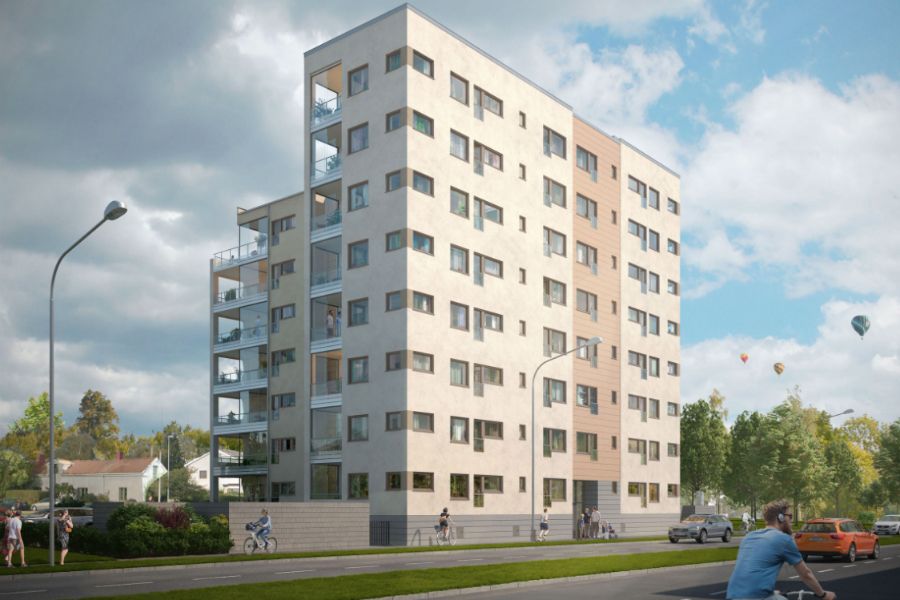 Modern flerfamiljshus med ljus fasad och balkonger, omgivet av grönska och en gata med cyklister och fotgängare under en blå himmel med moln och luftballonger