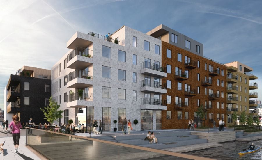 Modern flerfamiljshus vid en kanal med människor som promenerar och vistas på kajen i soligt väder