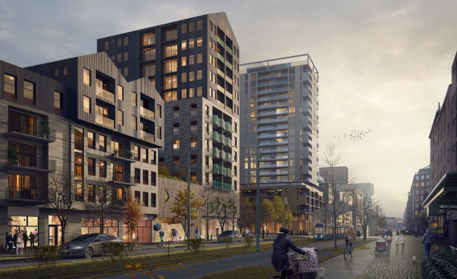 En stadsmiljö med moderna byggnader, cyklister och gångtrafikanter längs en bred väg i skymningsljus