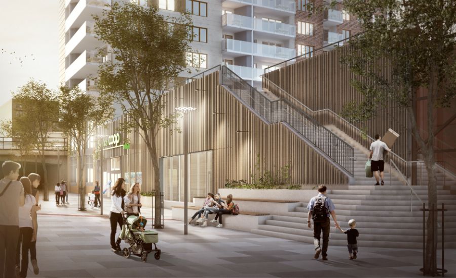 Utomhusmiljö med människor som promenerar, barnvagnar och en person som går uppför trappor vid moderna byggnader med trädplantering omkring