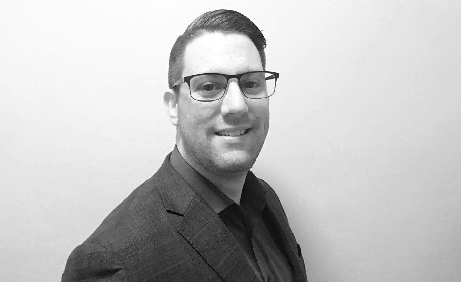 Man i kavaj och skjorta står mot en neutral, ljus bakgrund