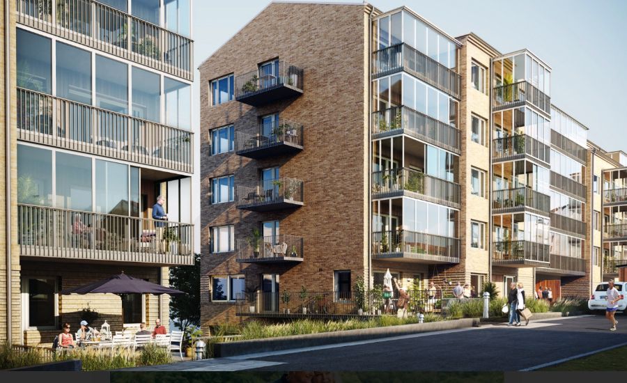 Flerfamiljshus med modern arkitektur, stora glaspartier och balkonger, omgivet av grönska och en gångväg