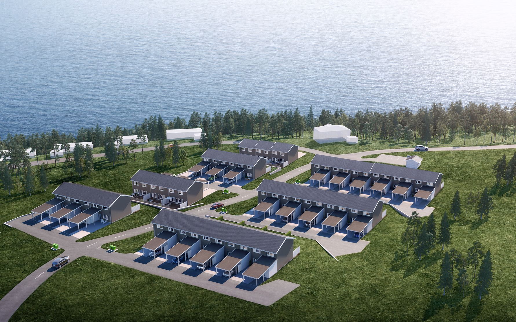 Radhusområde vid vattnet med flera byggnader, gräsmattor och en skog i bakgrunden