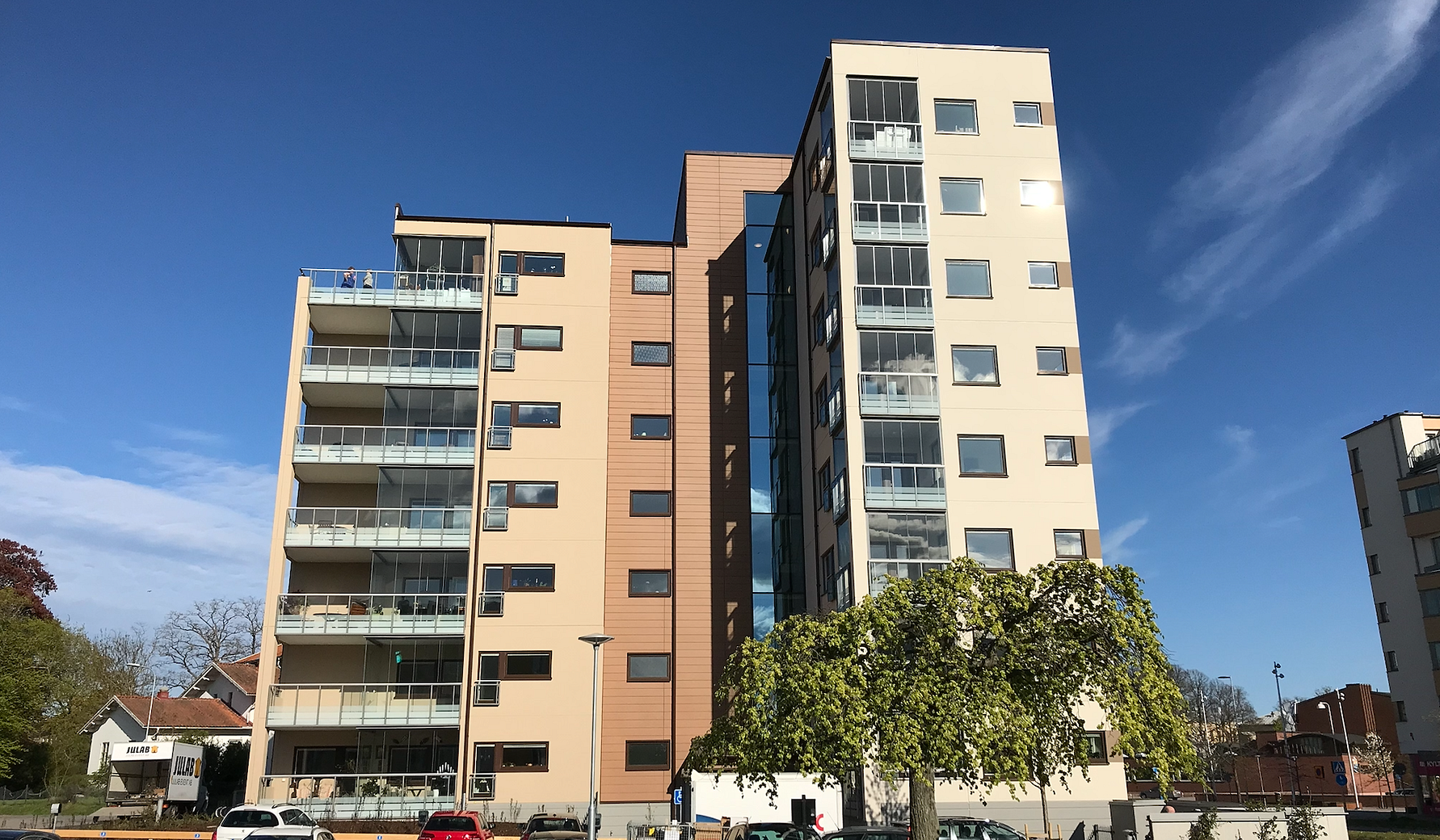 Flerbostadshus med moderna fasader, balkonger och stora fönster under en klar blå himmel