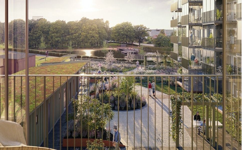 Bostadsområde med modern arkitektur, gröna tak, trädgårdar och gångvägar, beläget nära en park och vattendrag under solnedgång