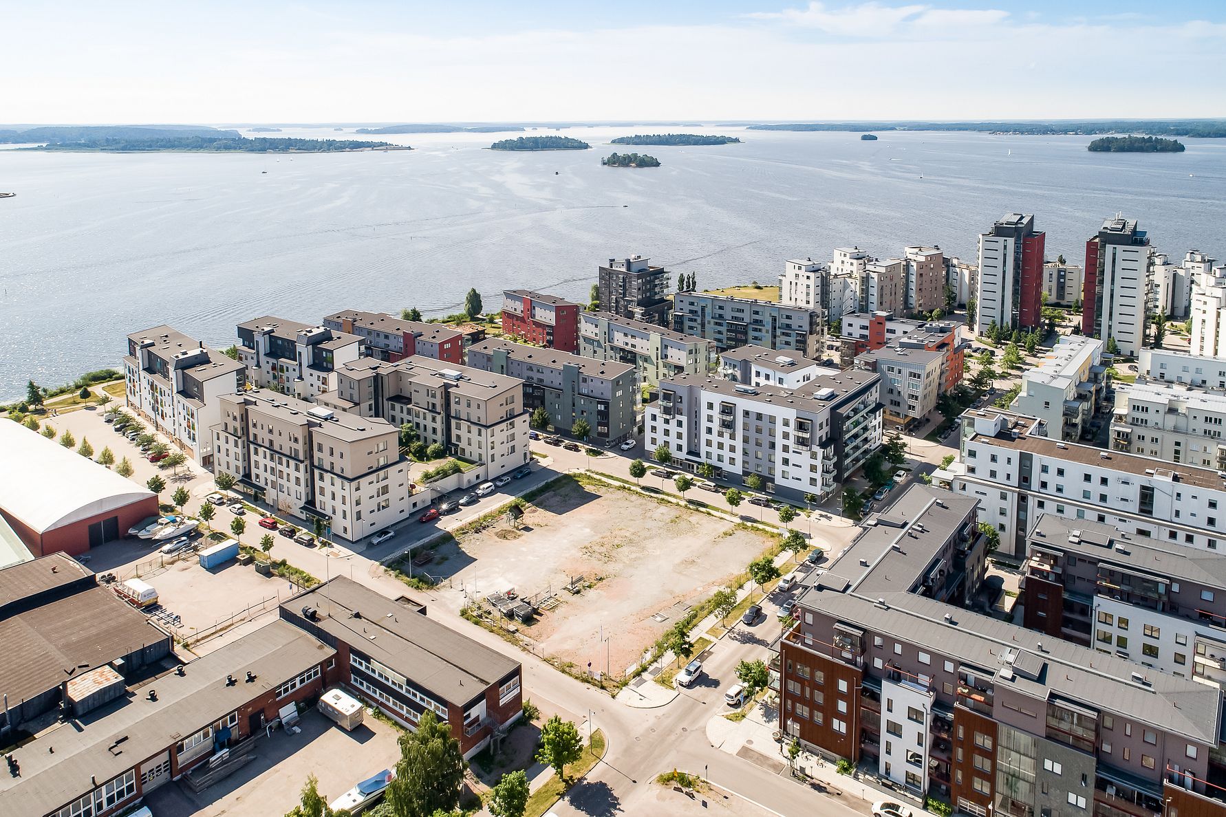 Flygbild över ett bostadsområde med moderna byggnader nära vattnet och små öar i bakgrunden