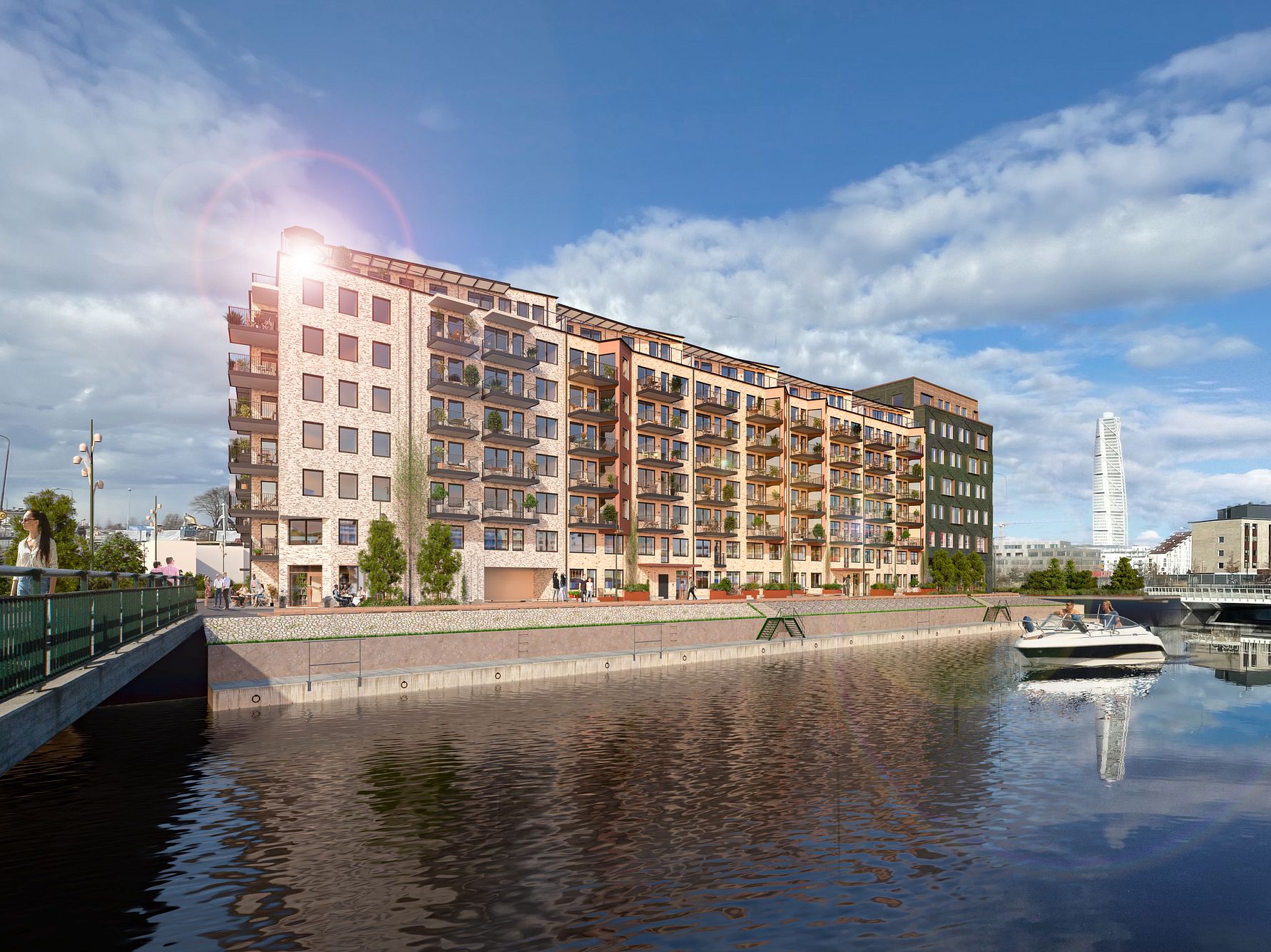 Nybyggda flerbostadshus vid vattnet under en klarblå himmel, med en båt på kanalen och Turning Torso synlig i bakgrunden