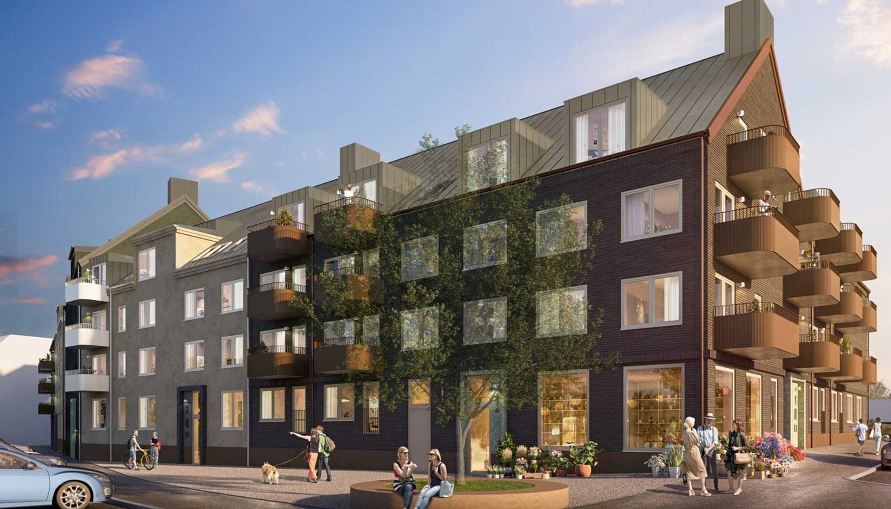 Nybyggd bostadsfastighet med flera våningar, balkonger och trädfylld omgivning under en klar himmel. Människor går och cyklar i området