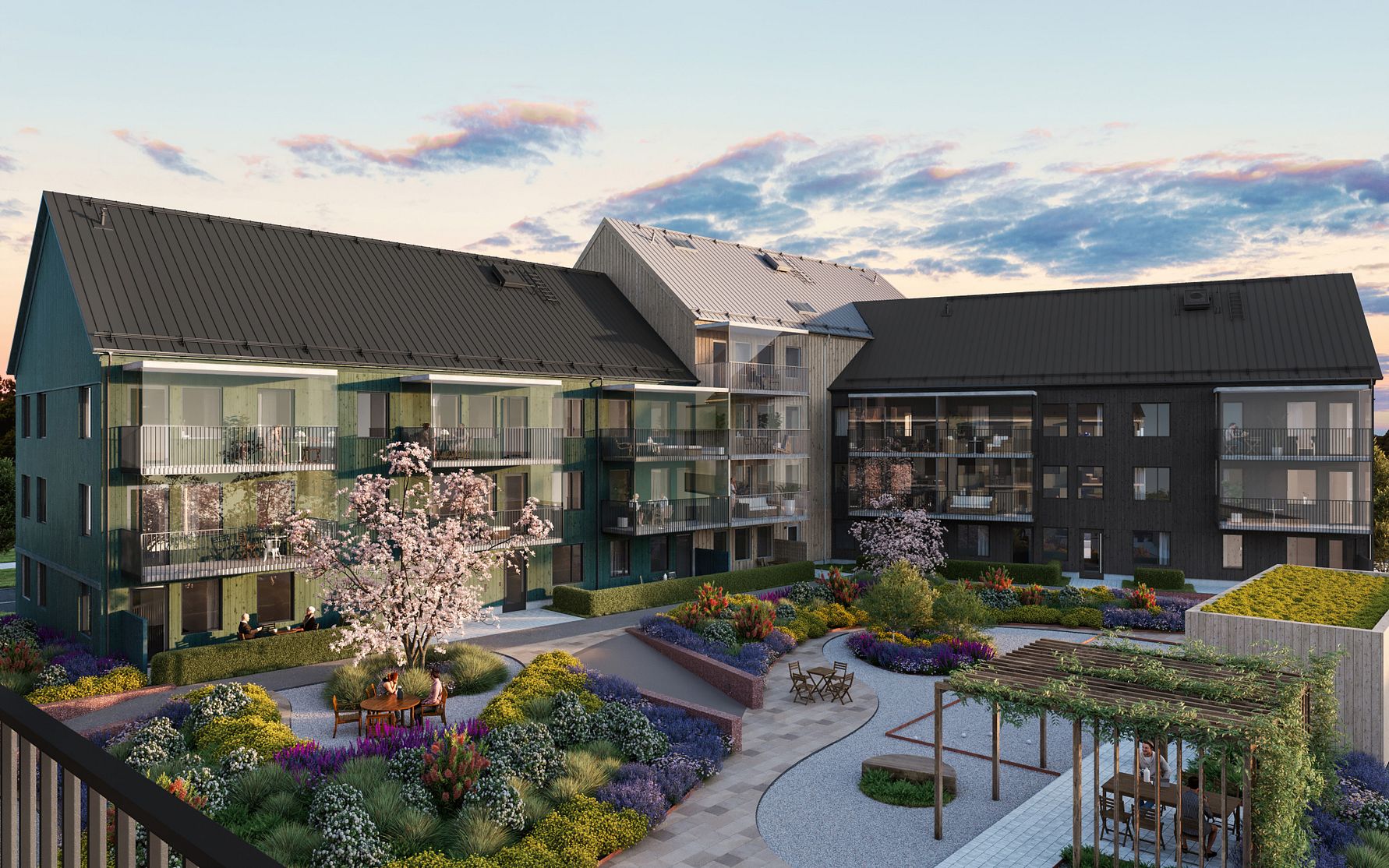 Modernt flerfamiljshus med mörka fasader och stora glaspartier, omgiven av en välskött trädgård med blommor, buskar och sittplatser under pergola