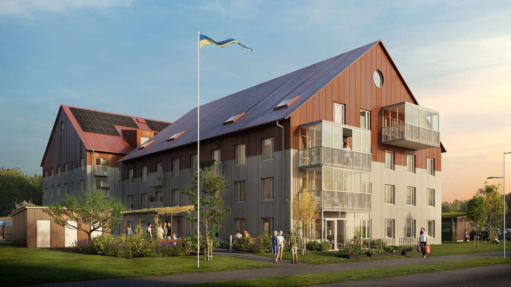 Modernt lägenhetskomplex med trä- och metallfasad, omgivna av träd och gräs, med en svensk flagga på en flaggstång i förgrunden